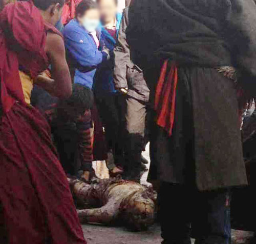 A women looks at the burned body of Dorje Rinchen following his self-immolation. 