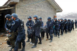 Tibetans being dragged away, bent double, by People's Armed police in riot gear.