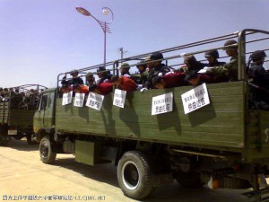 Monks bent double across the side of an open army truck, still with the placards announcing their "splittist" activities around their necks.